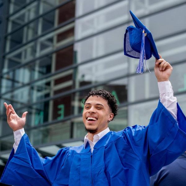 A Grand Valley grad spreads his arms in triumph in front of Van Andel Arena.
